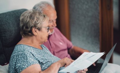 An elderly man and woman looking over a sheet of paper 